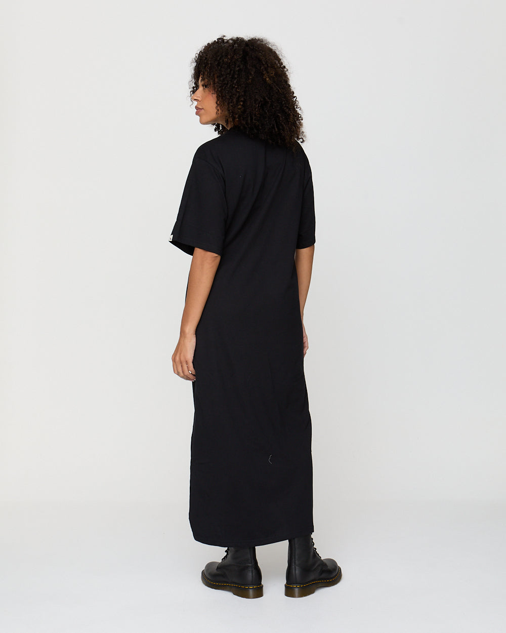 Person wearing a black dress standing against a white background