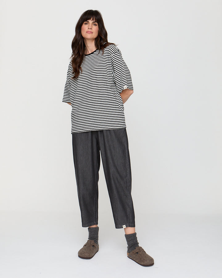 Woman wearing a black and white striped shirt and dark pants on a white background