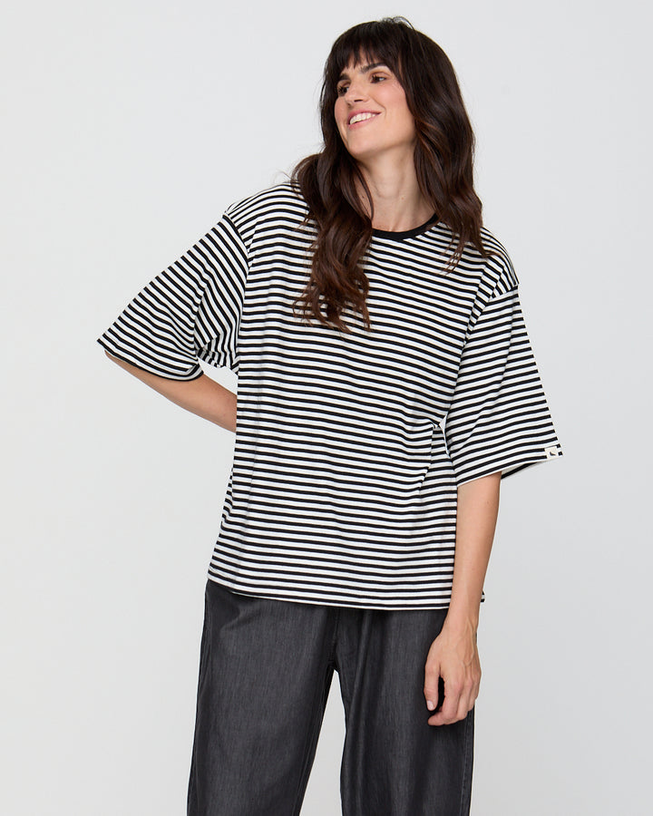 Woman wearing a black and white striped shirt against a plain background