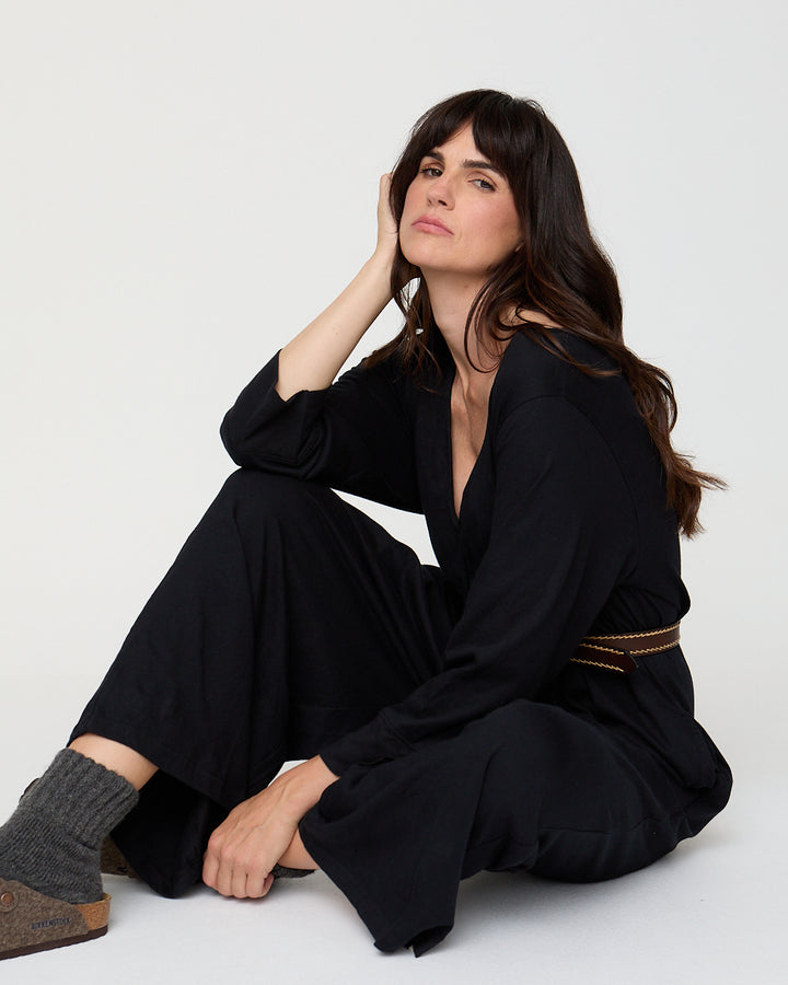 Woman wearing a black outfit sitting on a white background