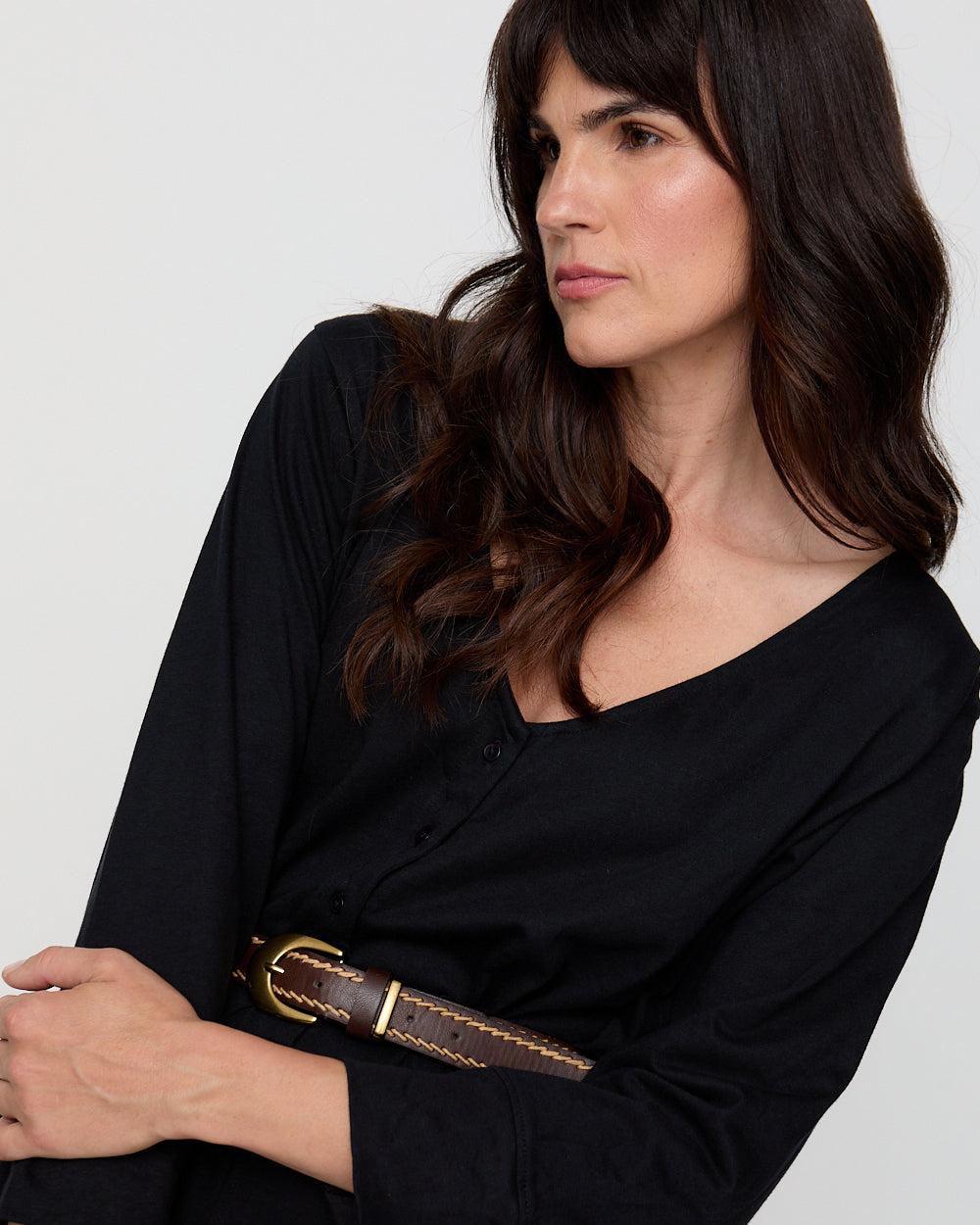 Woman wearing a black outfit with a brown belt against a white background