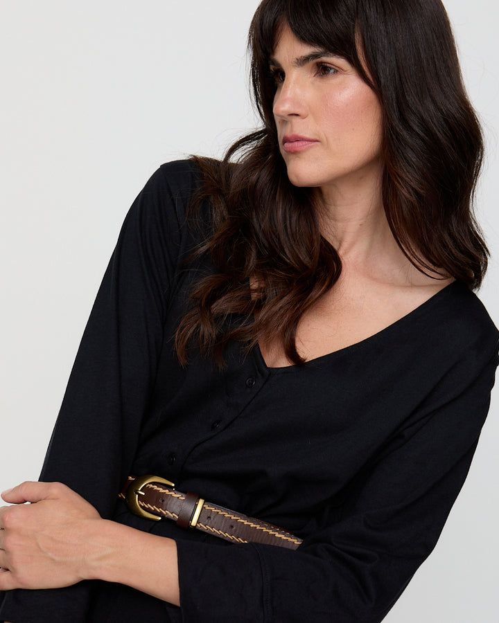 Woman wearing a black outfit with a brown belt against a white background