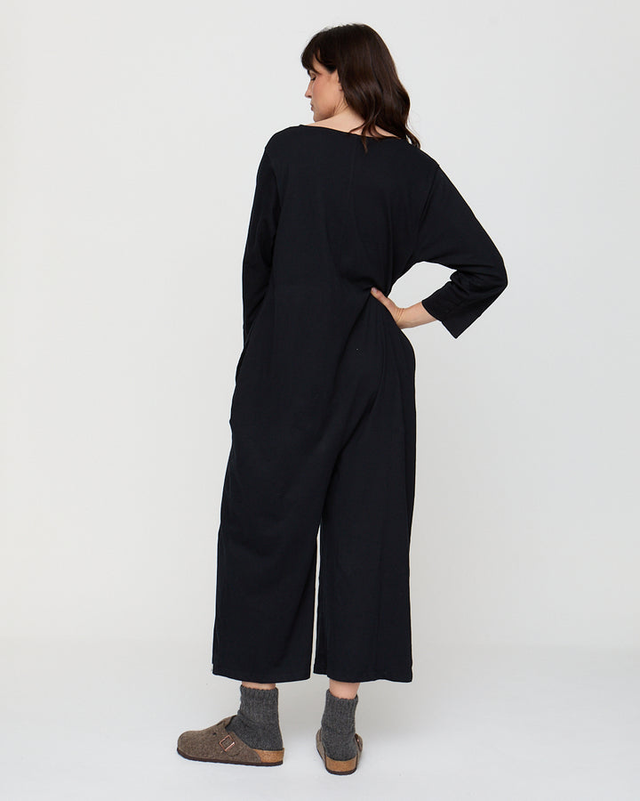 Person wearing a black jumpsuit on a white background