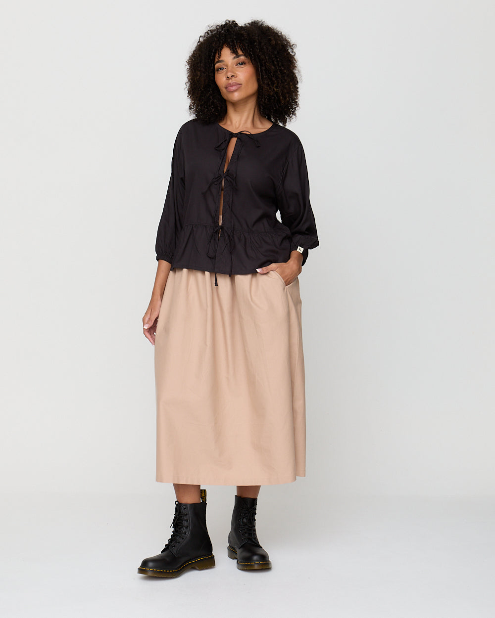 Woman wearing a black blouse and beige skirt on a white background