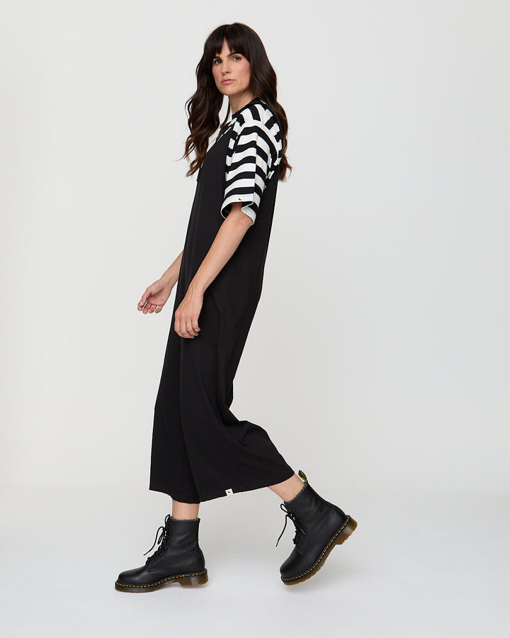 Woman wearing a black and white striped shirt with a black dress and black boots on a white background