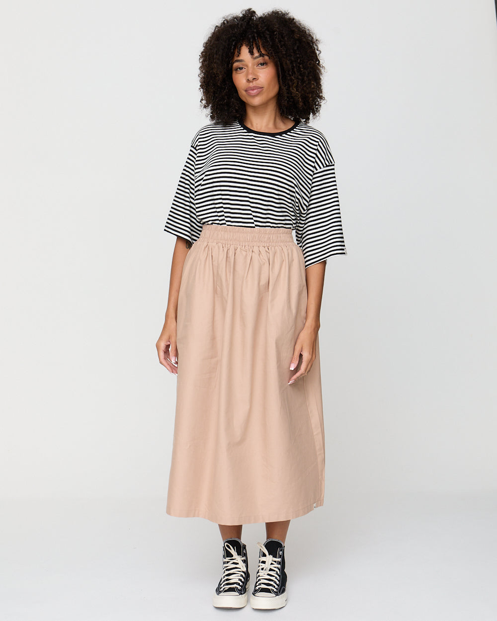 Woman wearing a striped shirt and beige skirt on a white background