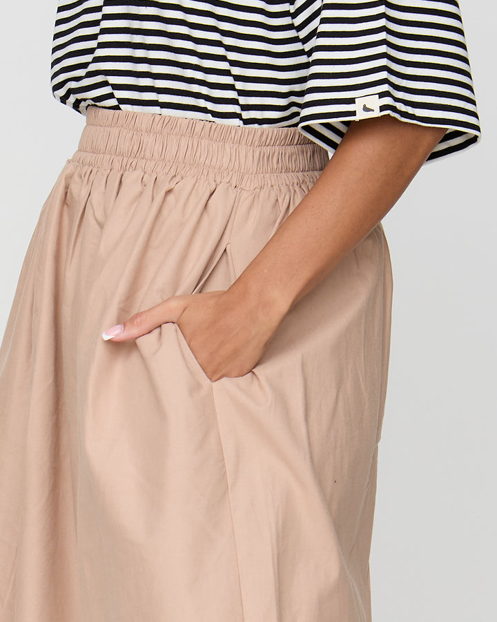 Person wearing a black and white striped shirt and beige pants with a plain background