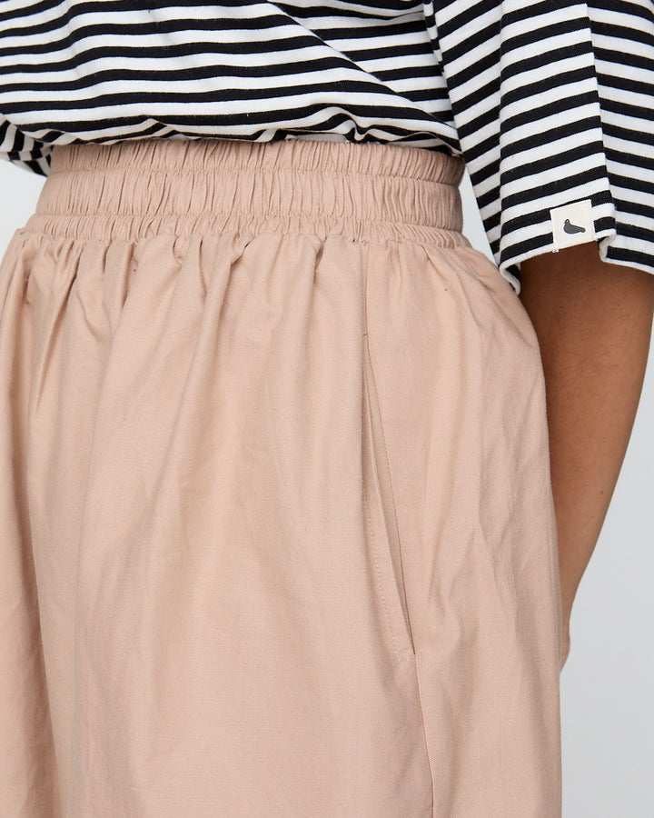 Beige pants worn with a black and white striped shirt on a plain background