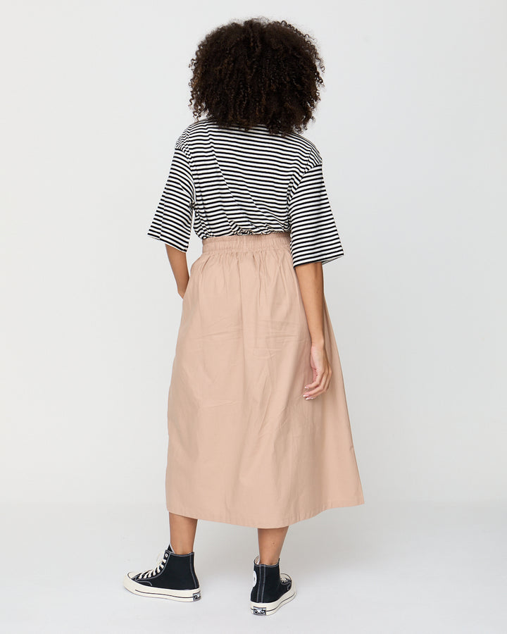 Person wearing a striped shirt and beige skirt on a white background