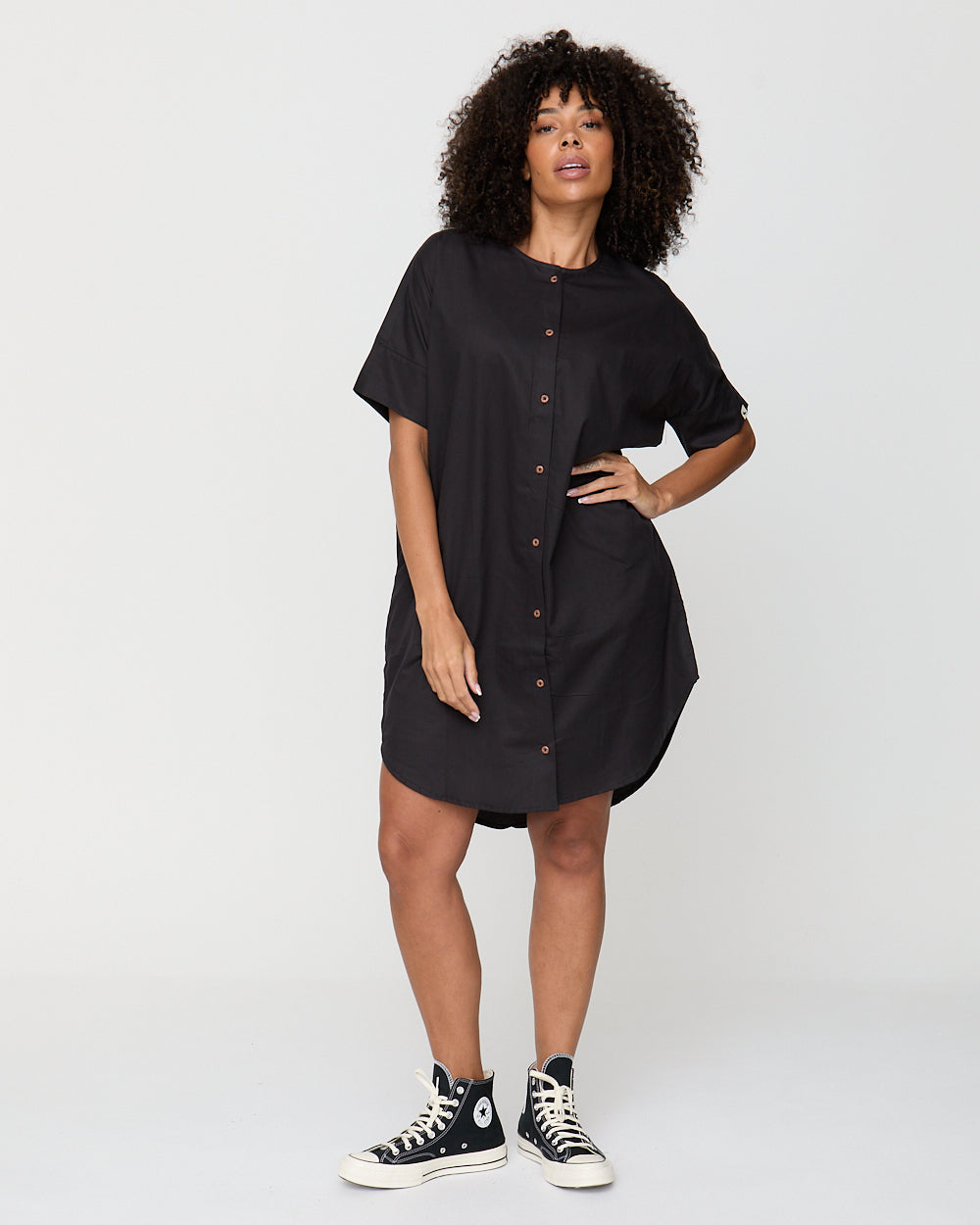 Woman wearing a black dress with buttons on a white background