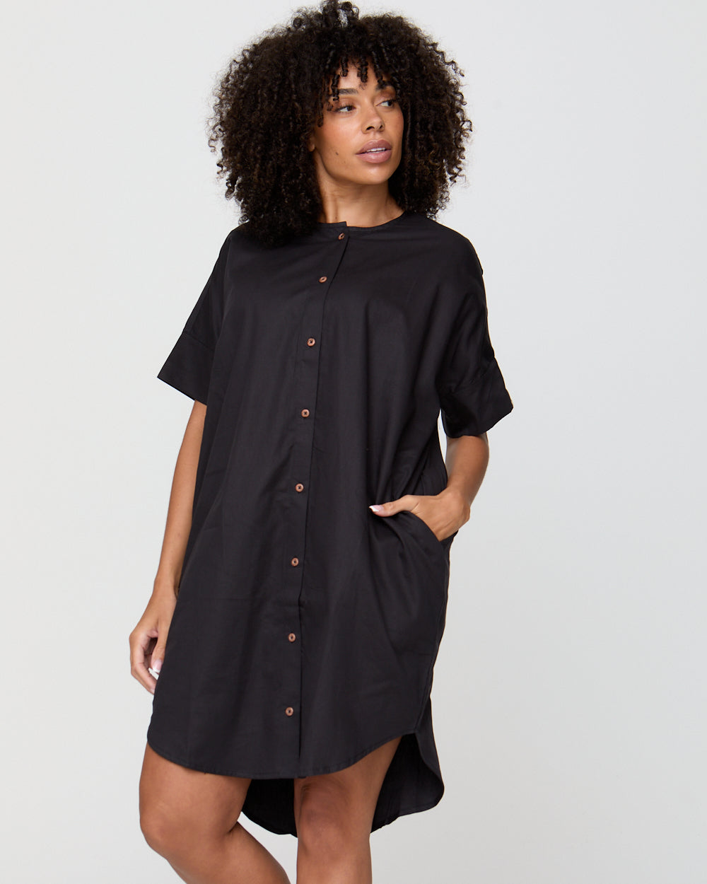 Woman wearing a black shirt dress against a white background