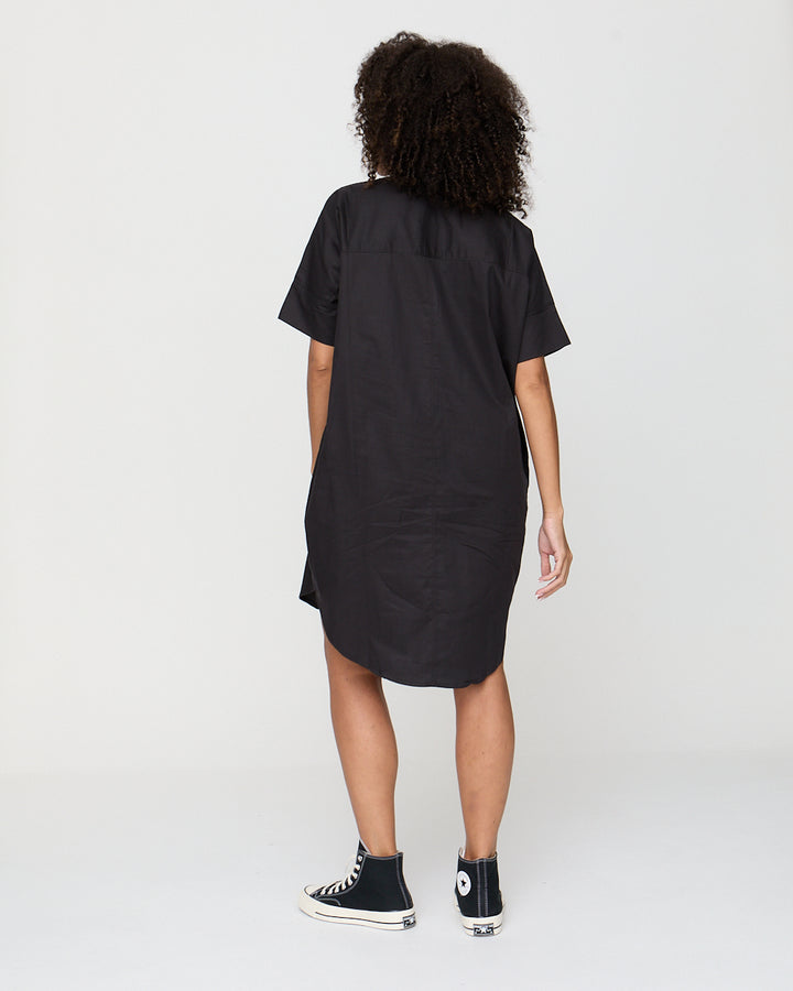 Person wearing a black dress with a plain white background