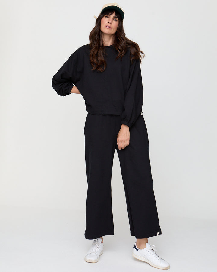 Woman wearing a black outfit with white sneakers on a white background