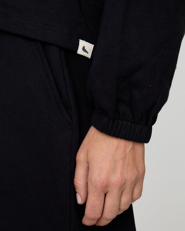 Close-up of a black sleeve with a brand logo on a plain background
