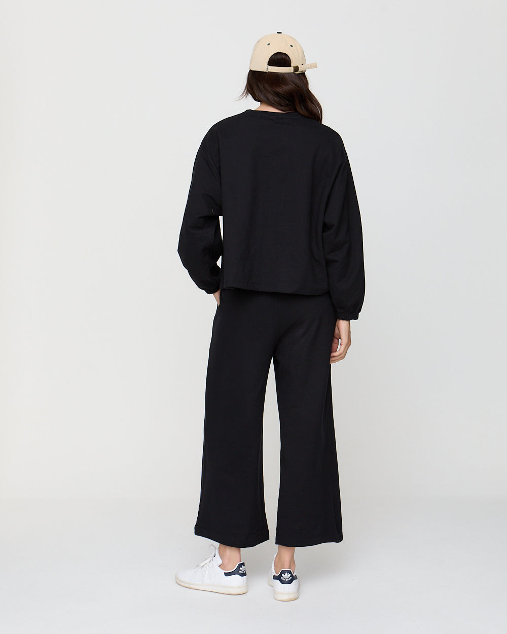 Person wearing a black outfit with wide-leg pants on a white background