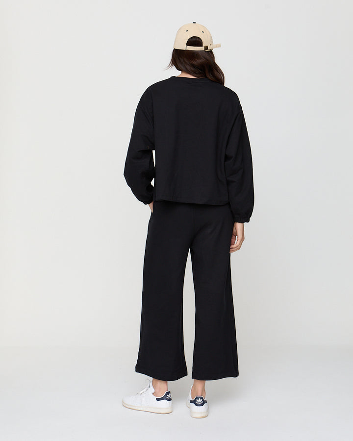 Person wearing a black outfit with wide-leg pants on a white background