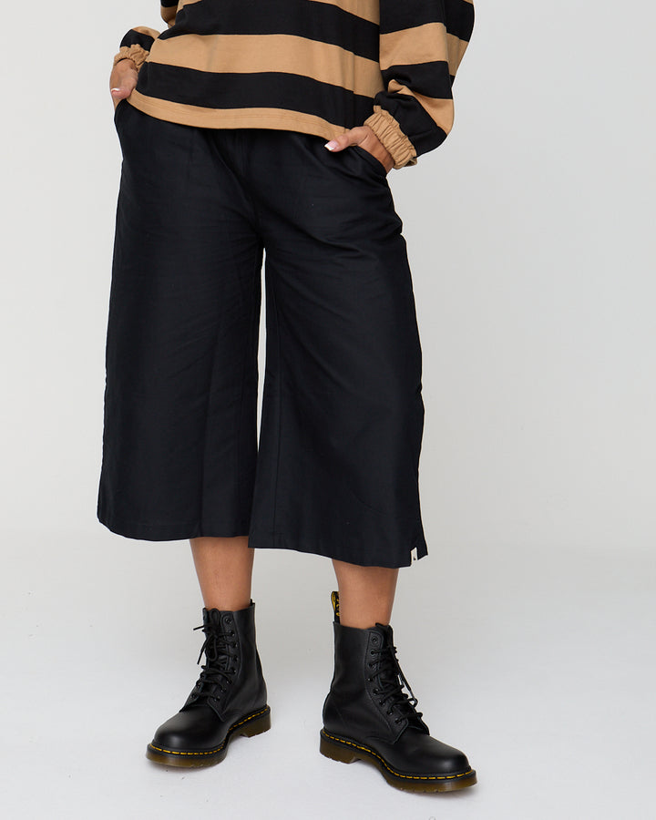 Person wearing a striped sweater, black pants, and black boots on a white background