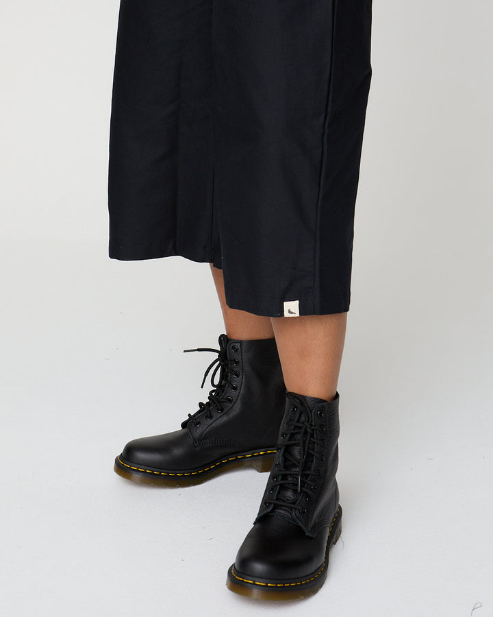 Person wearing black boots with yellow laces on a white background