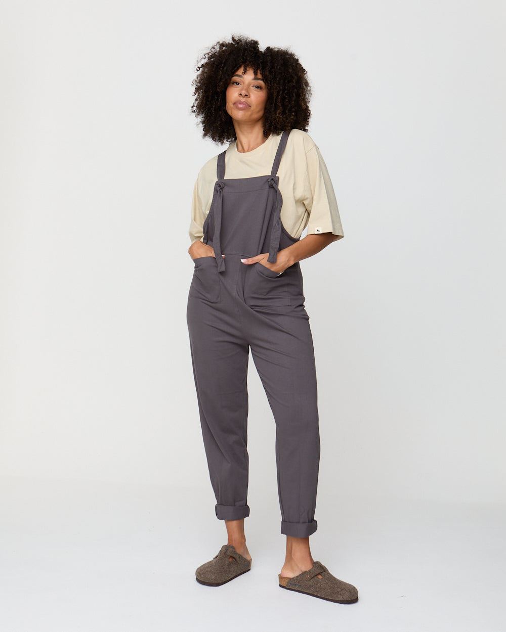 Person wearing gray overalls on a white background