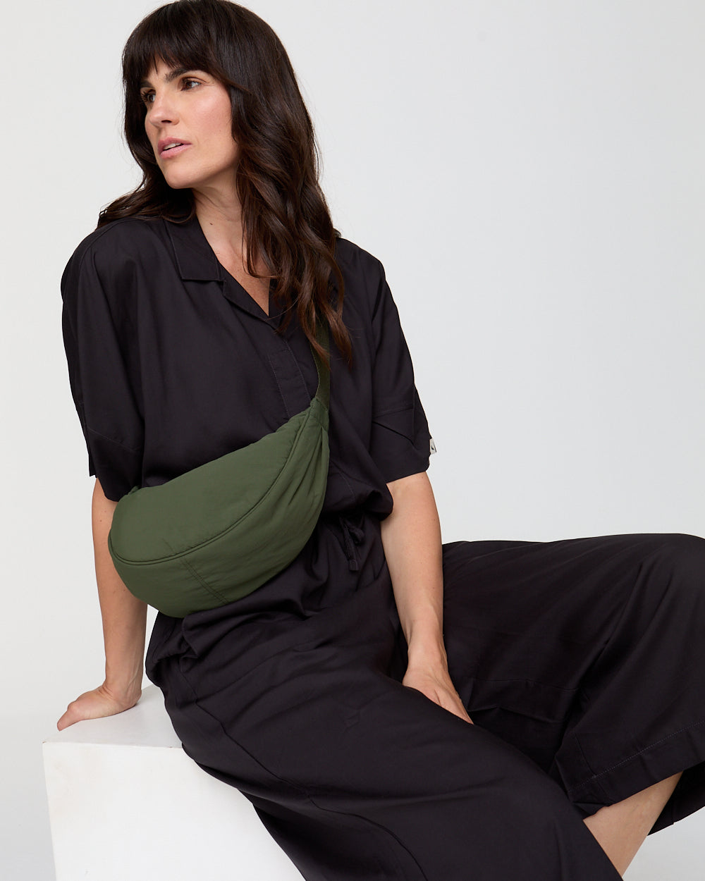 Woman wearing a black outfit with a green waist bag on a white background