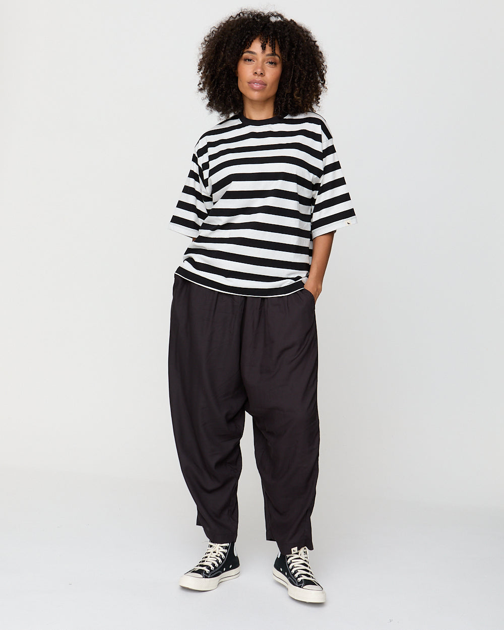 Person wearing a black and white striped shirt and black pants on a white background