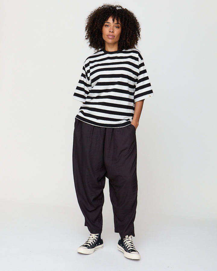 Person wearing a black and white striped shirt and black pants on a white background