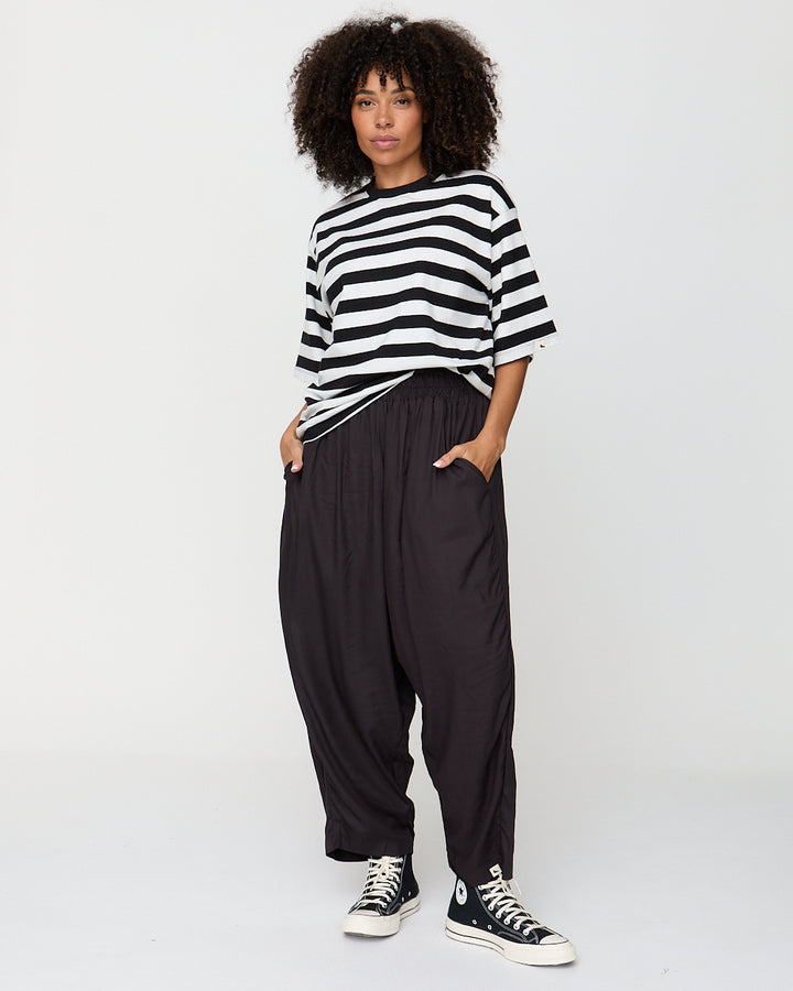 Person wearing a black and white striped shirt and black pants with Converse shoes on a plain background