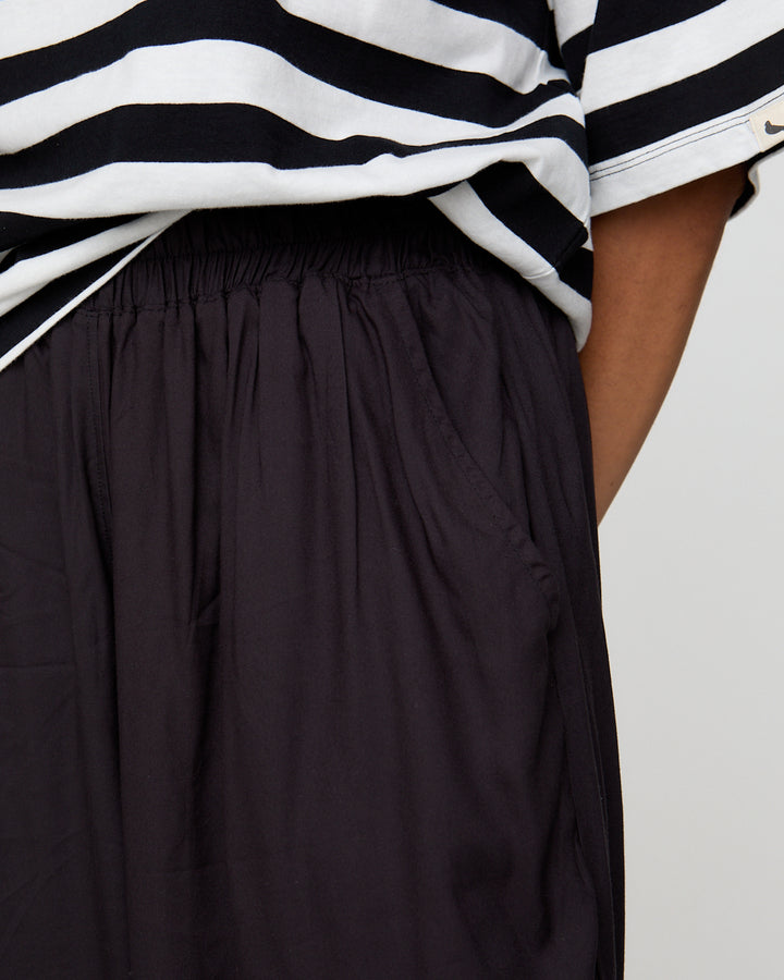 Person wearing a black and white striped shirt with a black skirt on a light gray background