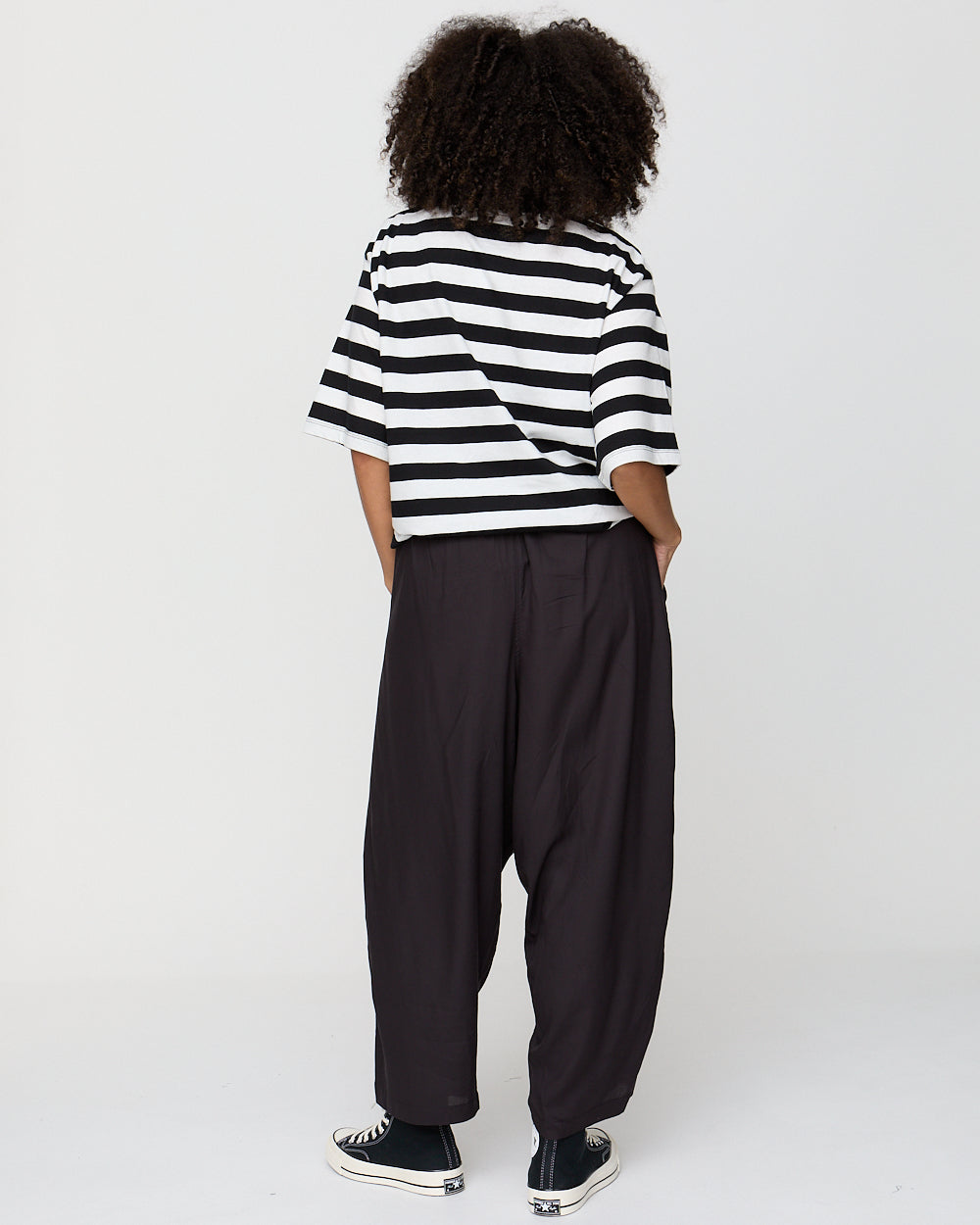 Person wearing a black and white striped shirt and black pants on a white background