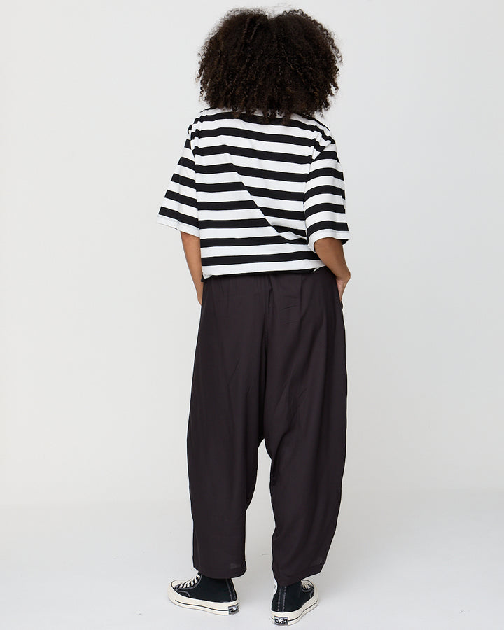 Person wearing a black and white striped shirt and black pants on a white background