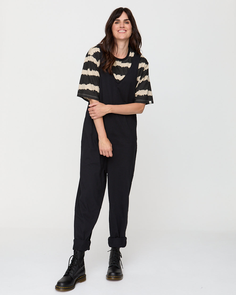Person wearing a black and beige striped sweater with black pants on a white background