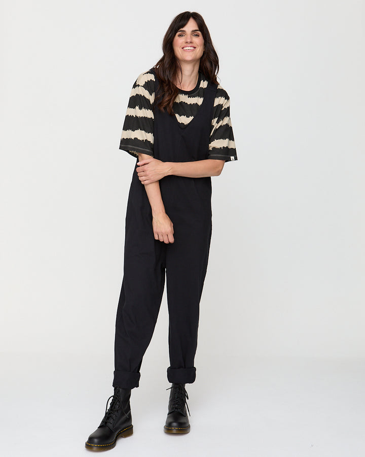 Person wearing a black and beige striped sweater with black pants on a white background