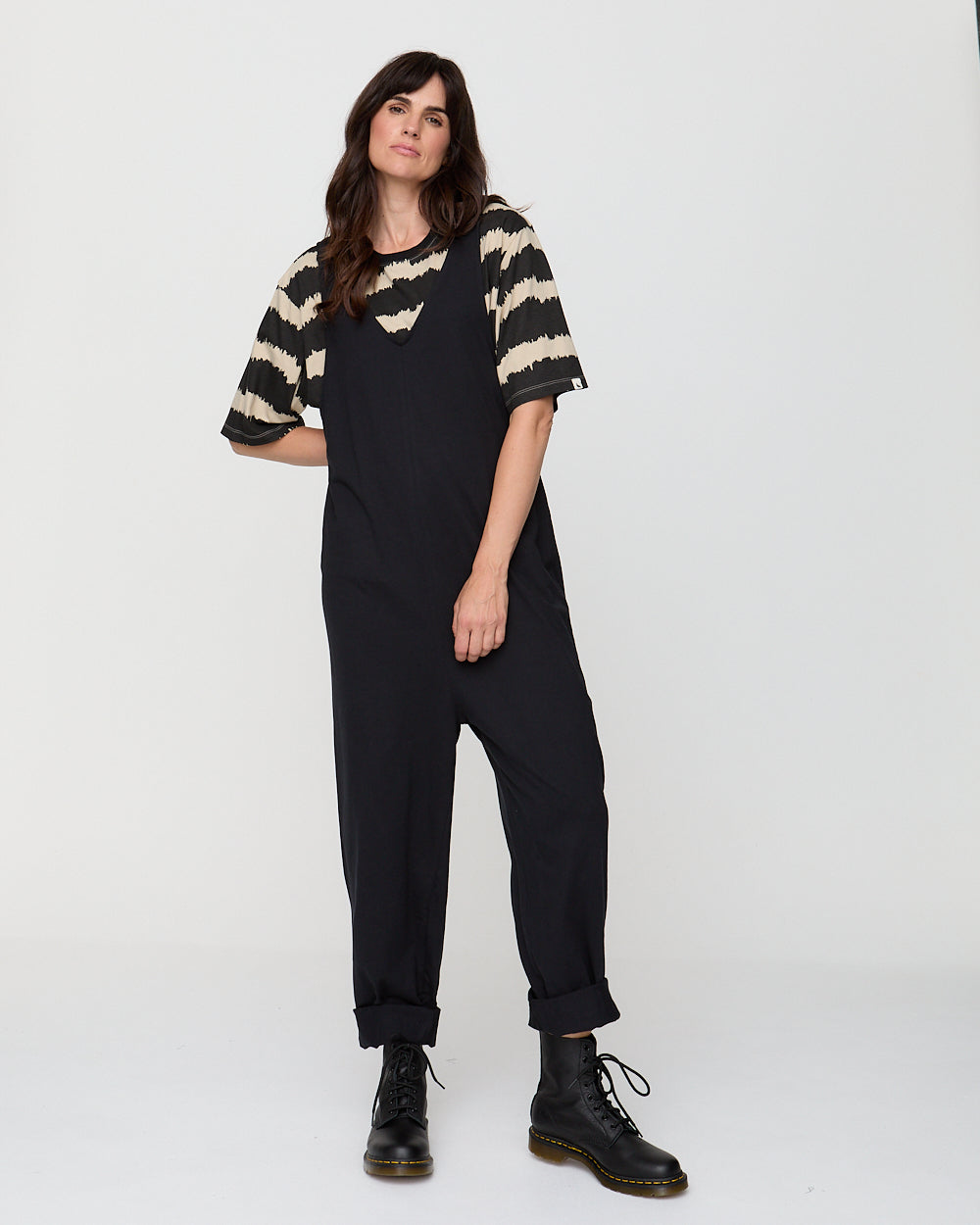 Woman wearing a black and beige striped shirt with black pants on a white background