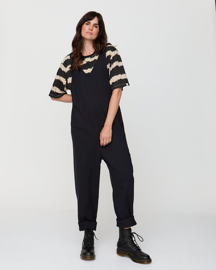 Woman wearing a black and beige striped shirt with black pants on a white background