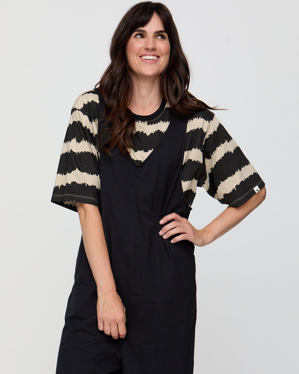 Woman wearing a black dress with beige striped sleeves against a white background