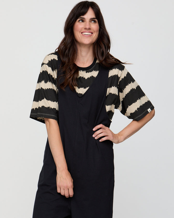 Woman wearing a black dress with beige striped sleeves against a white background