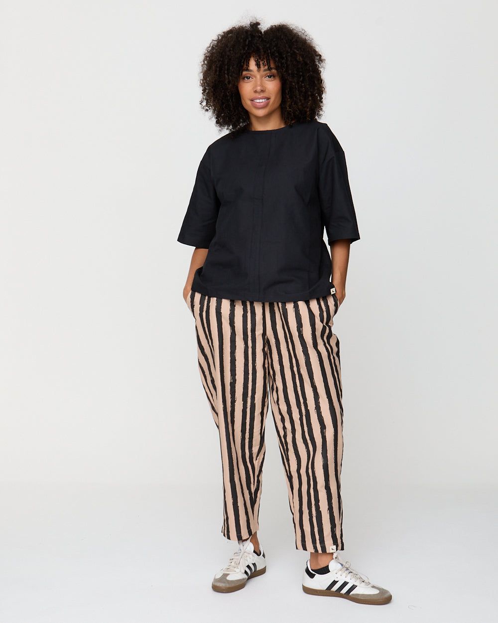 Person wearing a black t-shirt and striped pants on a white background