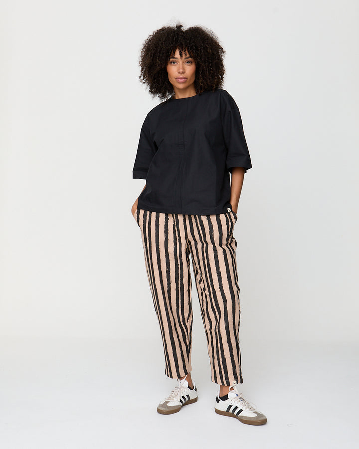 Person wearing a black oversized shirt and striped pants on a white background
