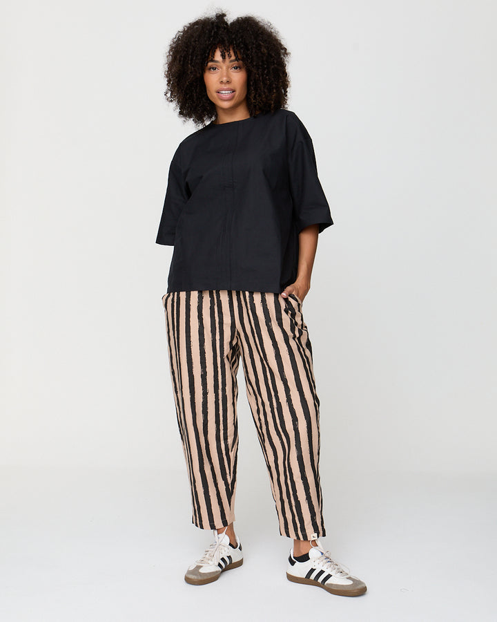 Person wearing a black top and striped pants on a white background