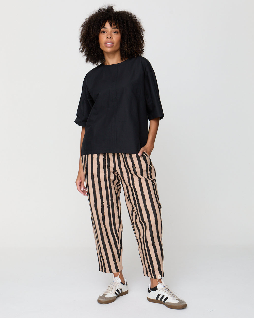 Person wearing a black top and striped pants on a white background