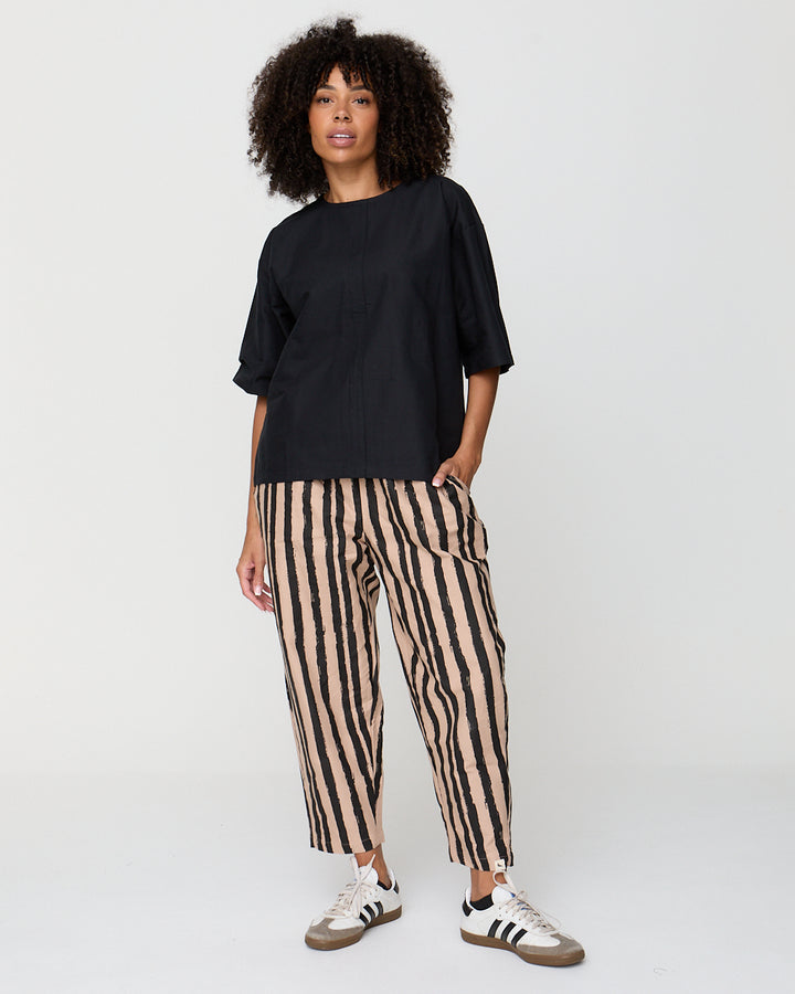 Person wearing a black top and striped pants on a white background