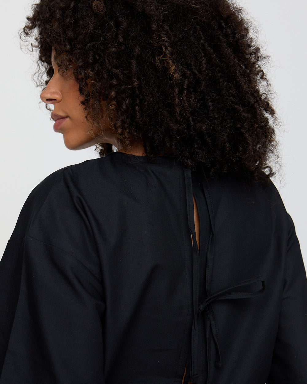 Person wearing a black jacket with a plain background