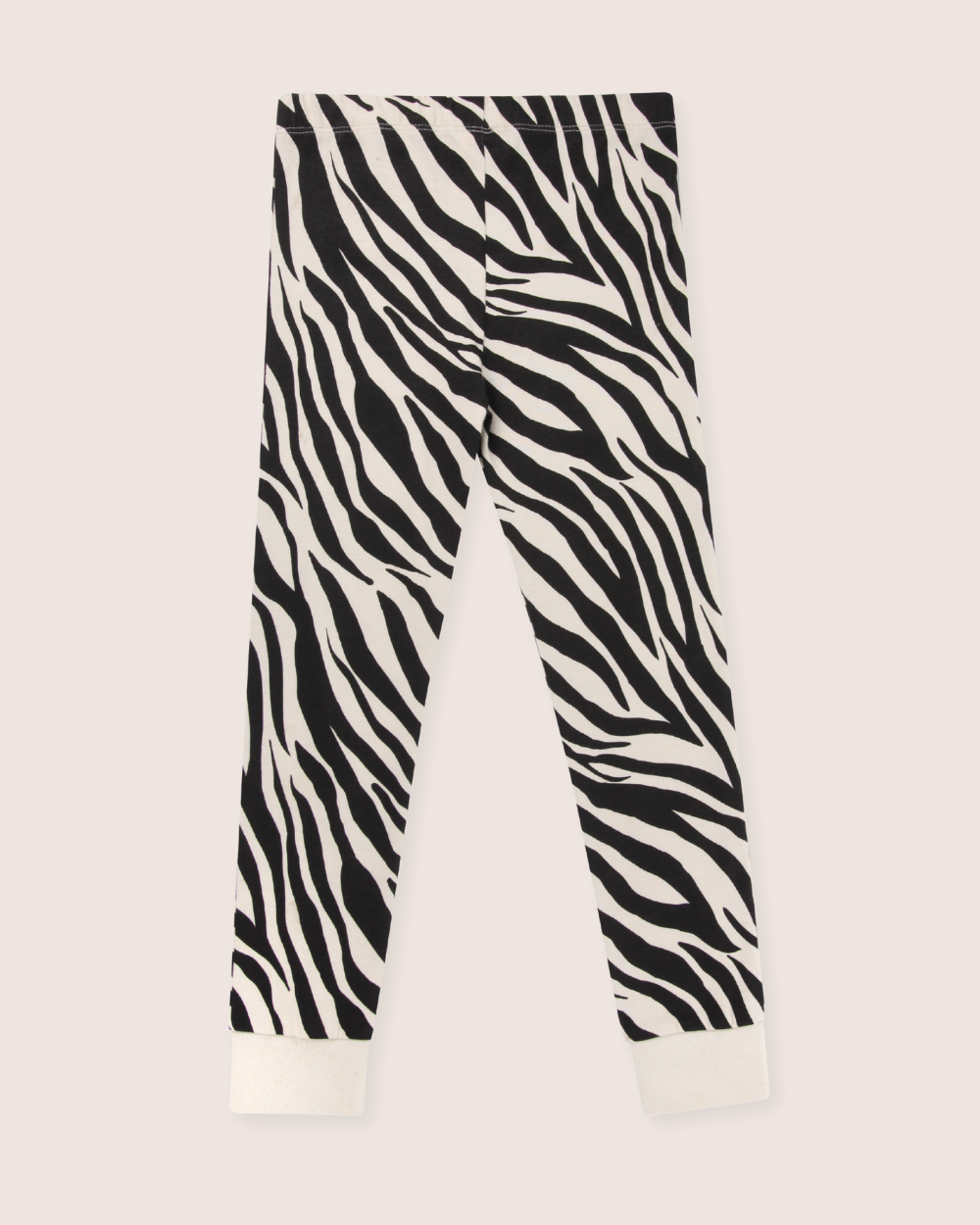 The Zebra Skin Leggings feature a bold, wavy black and white zebra skin print with white ankle cuffs. Crafted from organic cotton, they are designed for kids who love sustainable fashion and stand out against a light background.