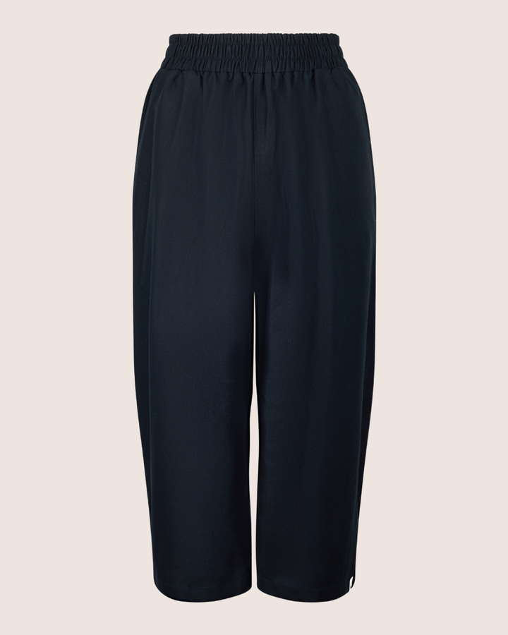 Judy Black Twill Trousers, designed from smooth, lightweight organic cotton, feature a loose-fitting culotte style with an elasticated waistband, showcased against a plain background.