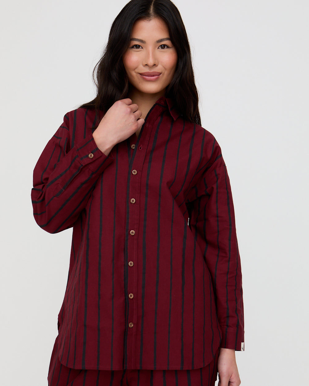 Woman wearing a burgundy striped shirt against a white background