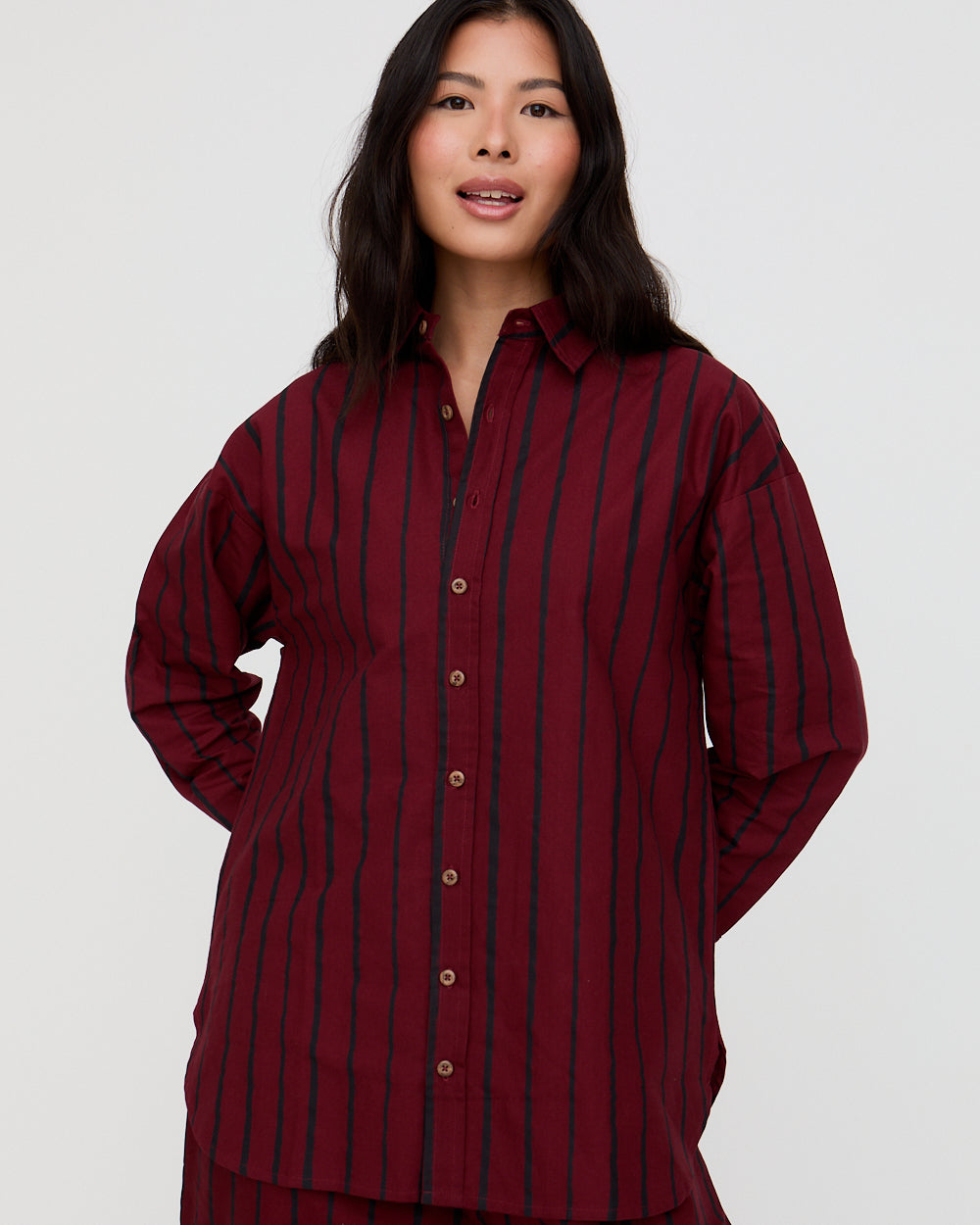 Woman wearing a burgundy and navy striped shirt against a white background