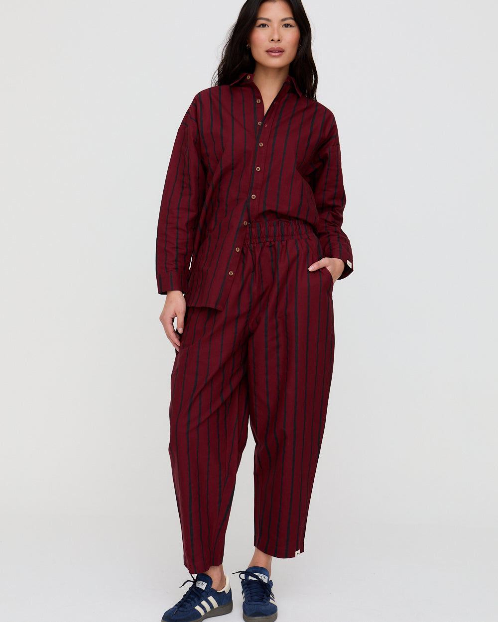 Woman wearing a burgundy and navy striped outfit on a white background