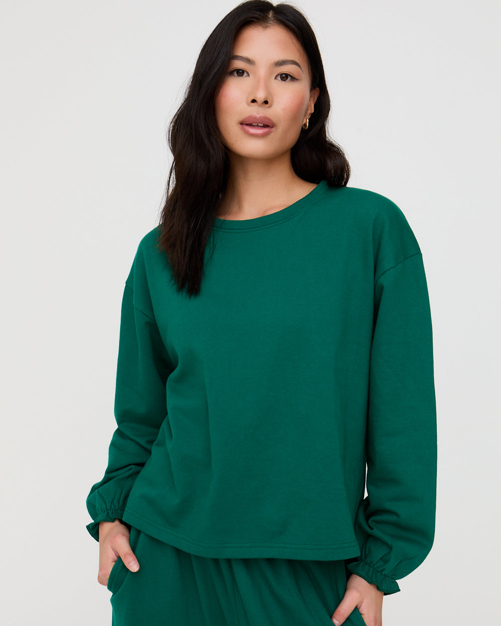 Woman wearing a green sweatshirt against a white background