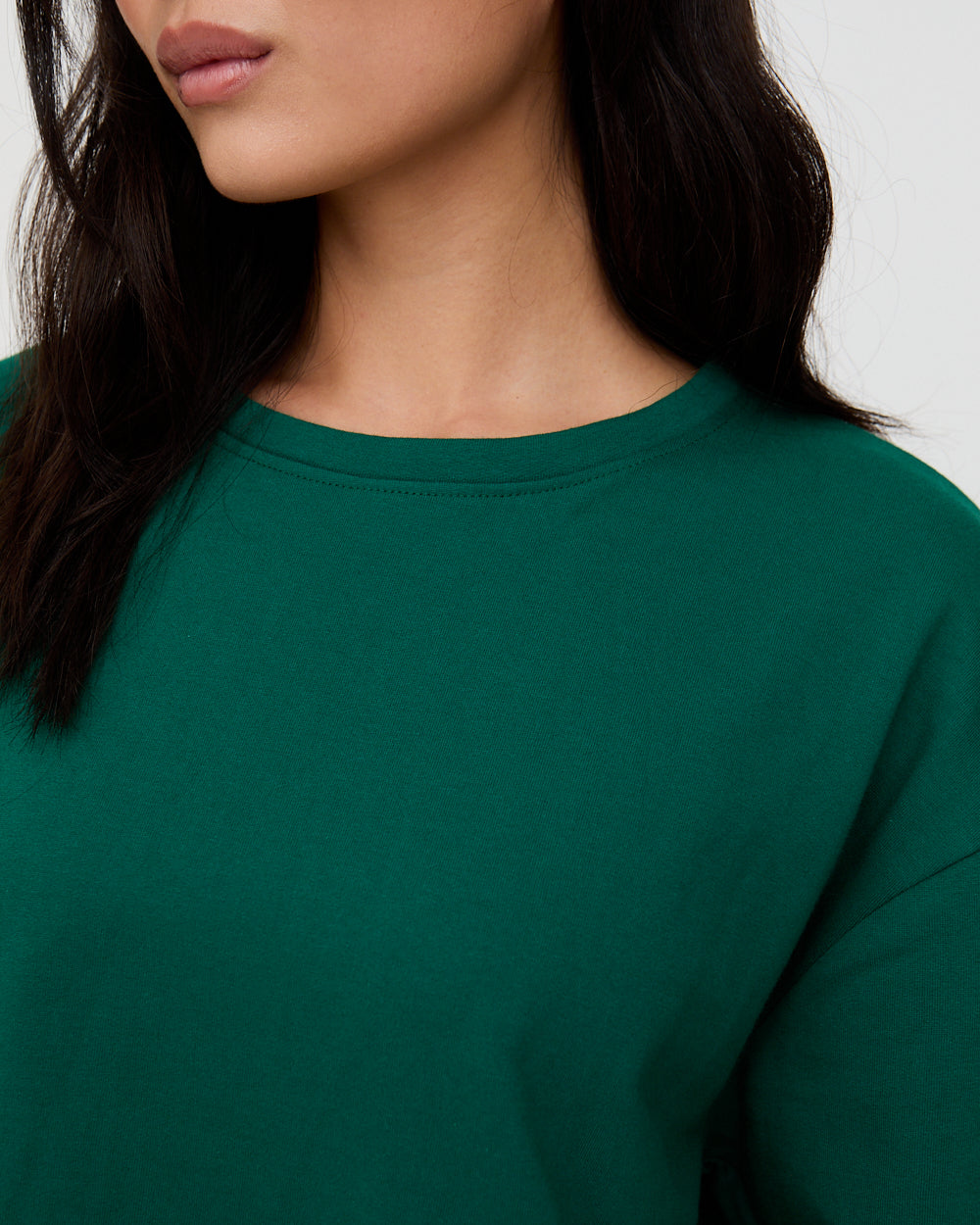 Close-up of a person wearing a green sweatshirt against a neutral background