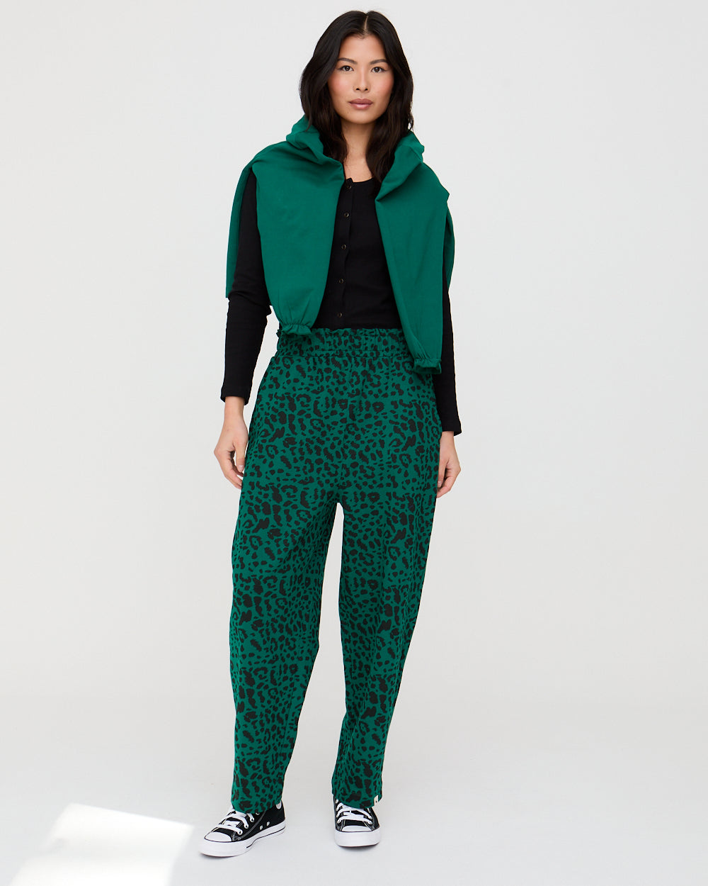 Person wearing a green jacket and leopard print pants on a white background